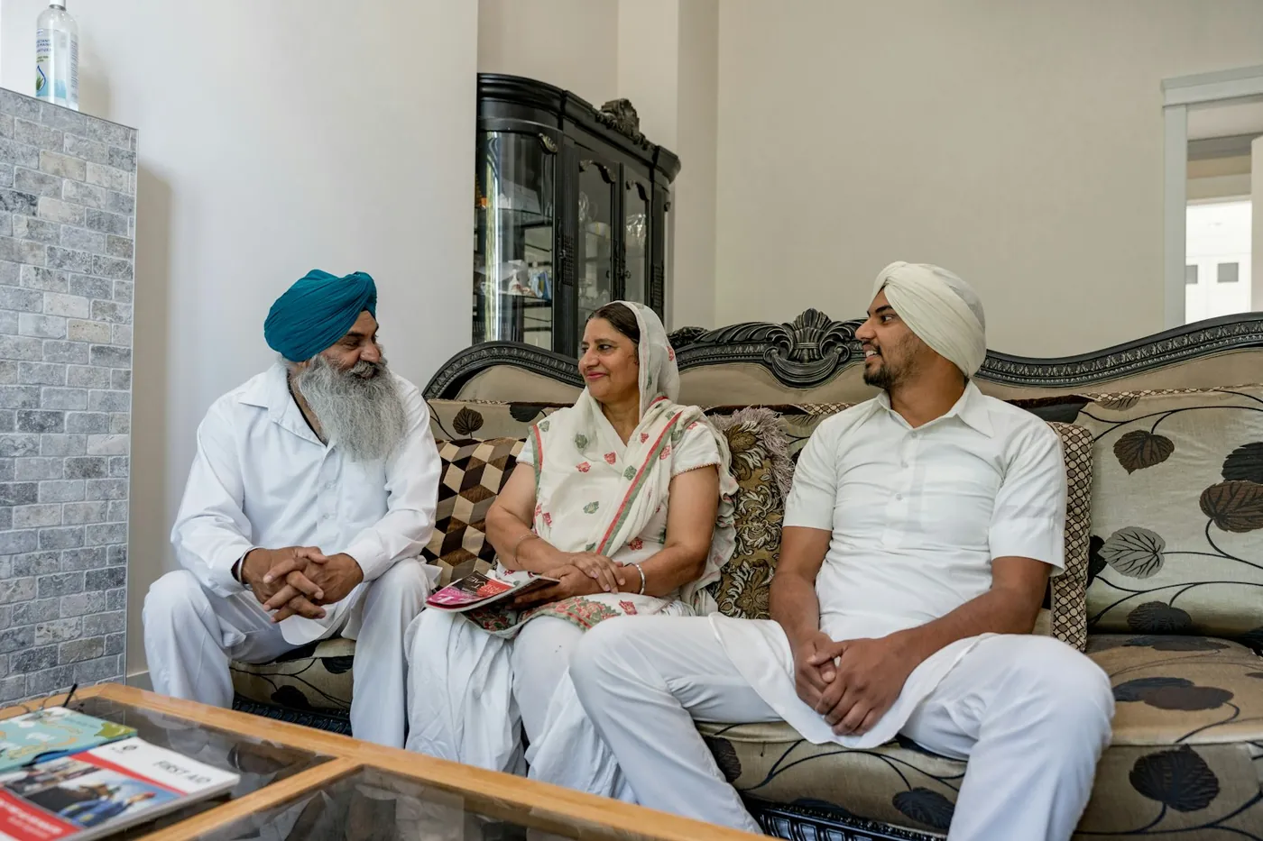 Three generations of a British Indian family sitting together in their living room